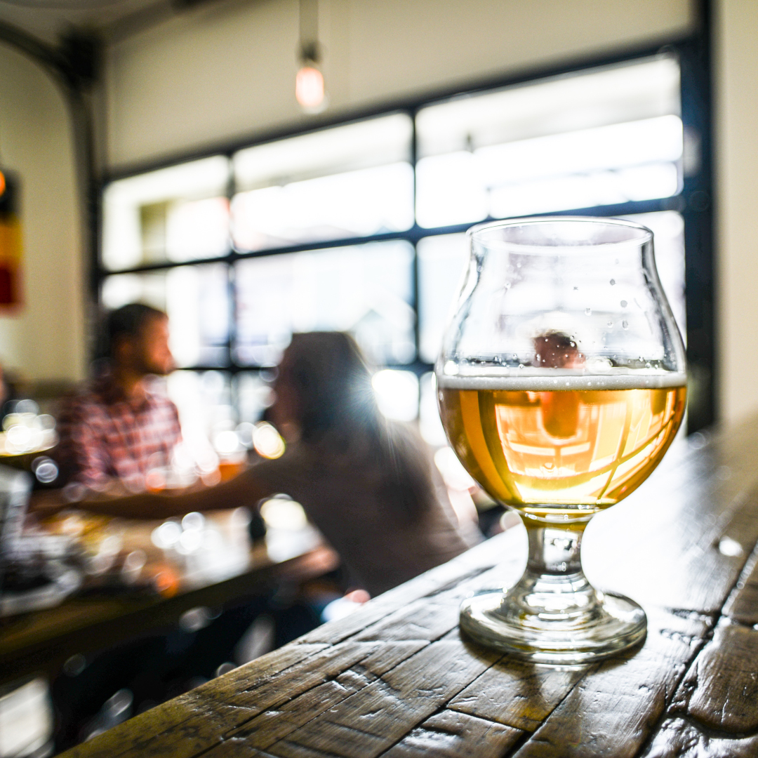 glass of beer with brewery patrons in the background